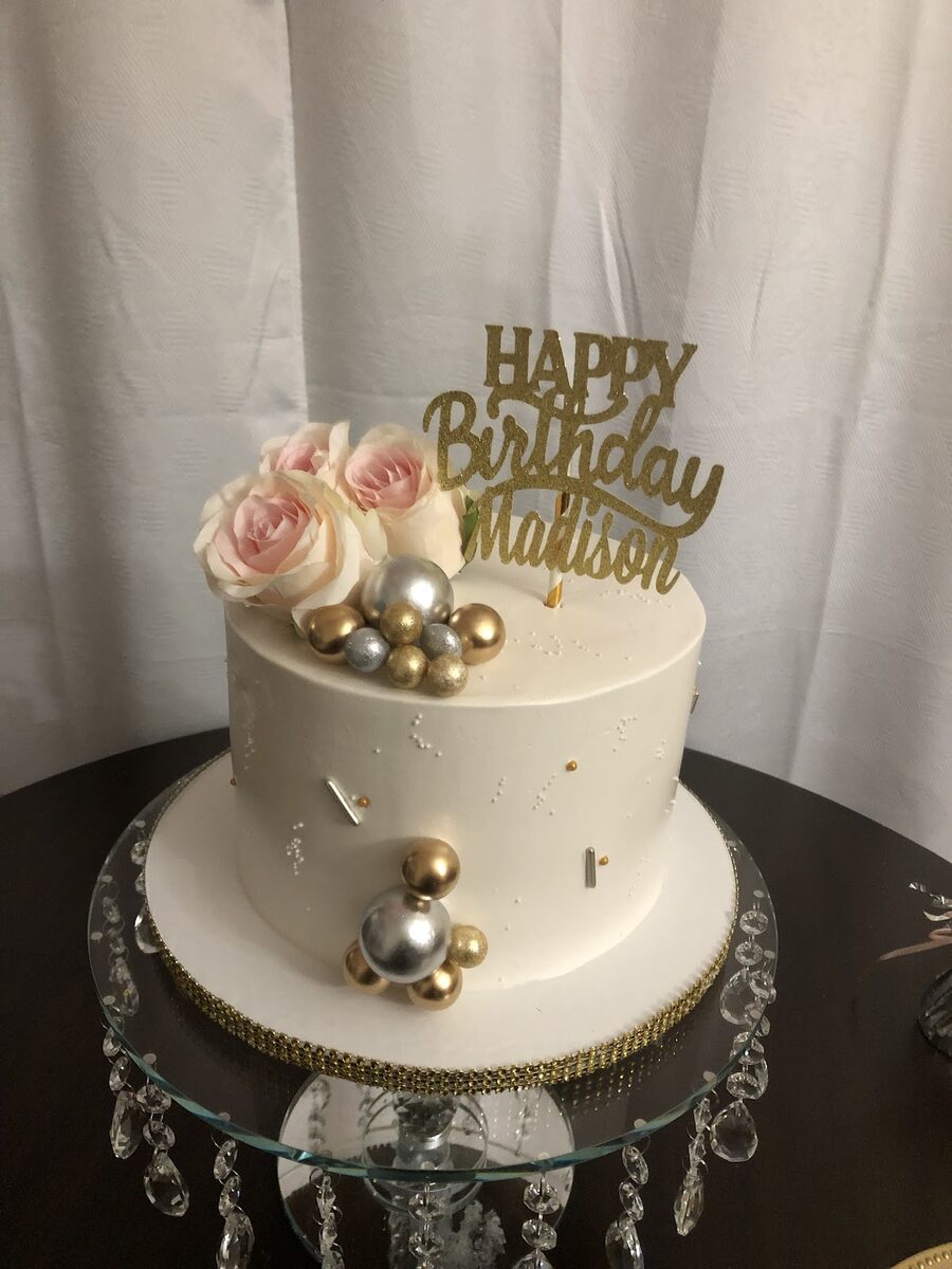 White and gold birthday cake with sugar pearls on a chandelier stand